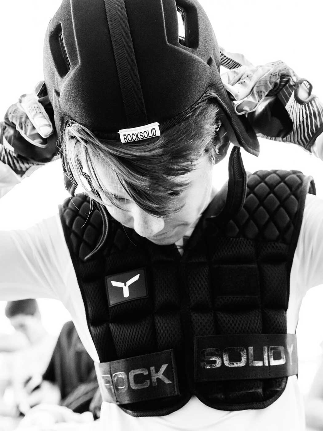 Athlete putting on Rocksolid RS2 headgear while wearing the RSS shoulder pad