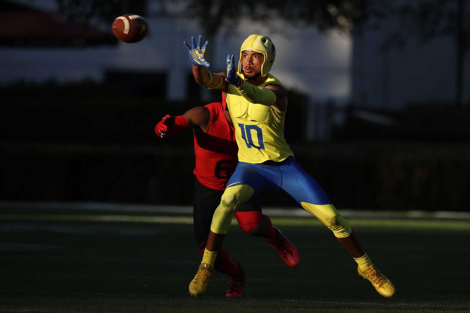 Athlete in gold Rocksolid soft shell headgear reaching for a football