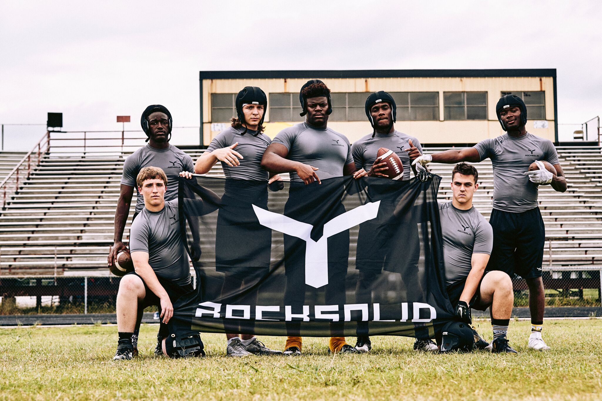 Athletes holding the Rocksolid flag beside the field